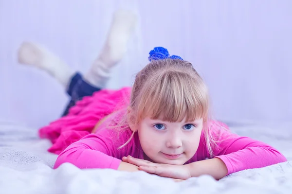 Smiling little girl lying on bed — Stock Photo, Image