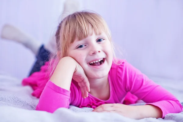 Sorrindo menina deitada na cama — Fotografia de Stock