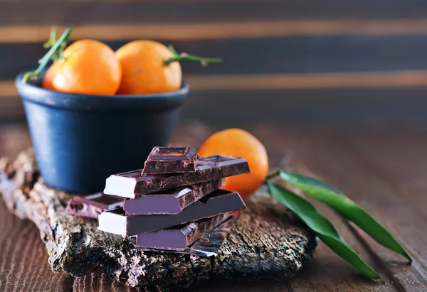 Chocolate and tangerines on the wooden board — Stock Photo, Image