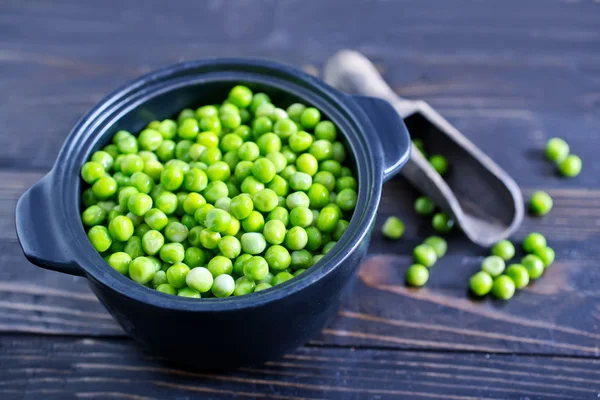 Green peas in black ceramic bowl — Stock Photo, Image
