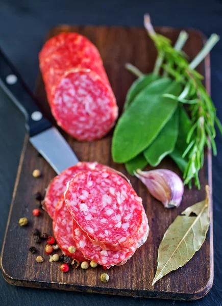 Salami and knife on table — Stock Photo, Image