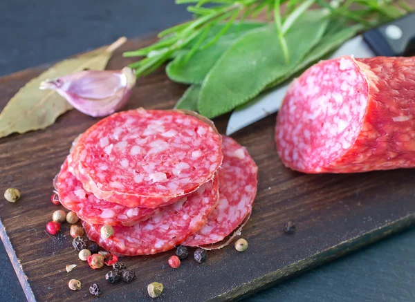 Salami and knife on table — Stock Photo, Image