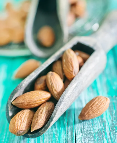 Almond in spoon and on a table — Stock Photo, Image