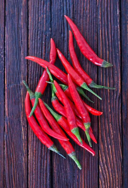 Chilli papričky na dřevěný stůl — Stock fotografie