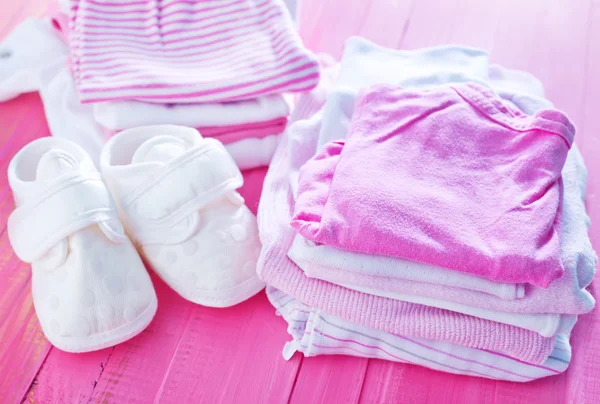 Ropa de bebé en la mesa rosa —  Fotos de Stock