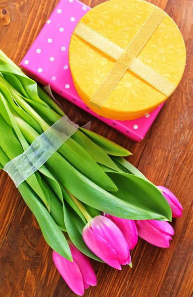 Presente y tulipanes sobre la mesa —  Fotos de Stock