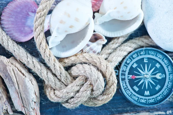 Zeeschelpen en kompas op een tafel — Stockfoto