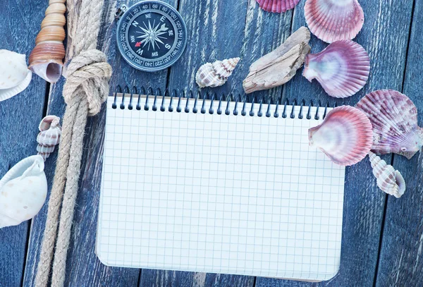 Zeeschelpen en kompas op een tafel — Stockfoto