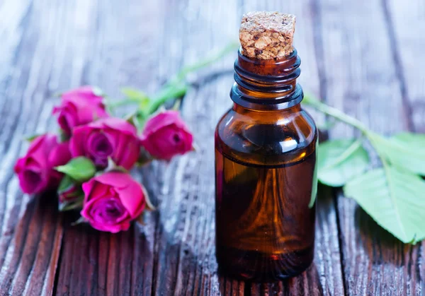 Růžového oleje v láhvi a na stole — Stock fotografie