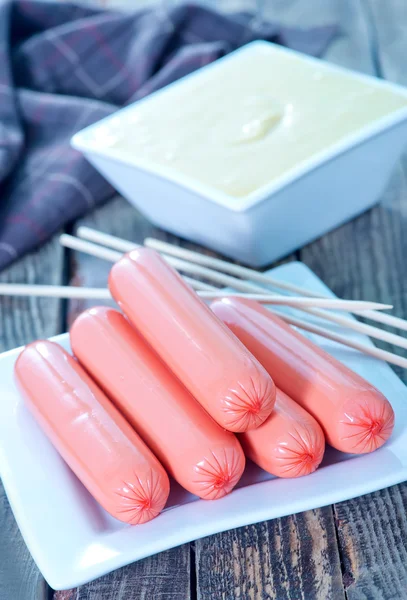 Sausages on plate and on a table — Stock Photo, Image