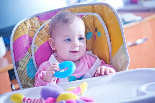 Baby i köksstol med leksaker — Stockfoto