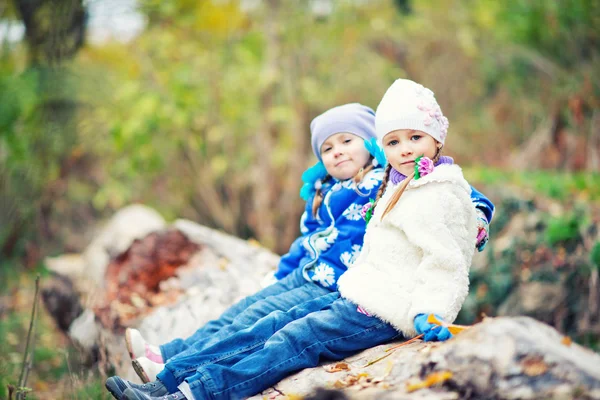 Little sisters sitting on log — Stock Photo, Image