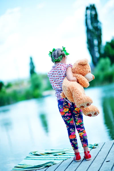 Girl on  pier with teddy bear — Stock Photo, Image