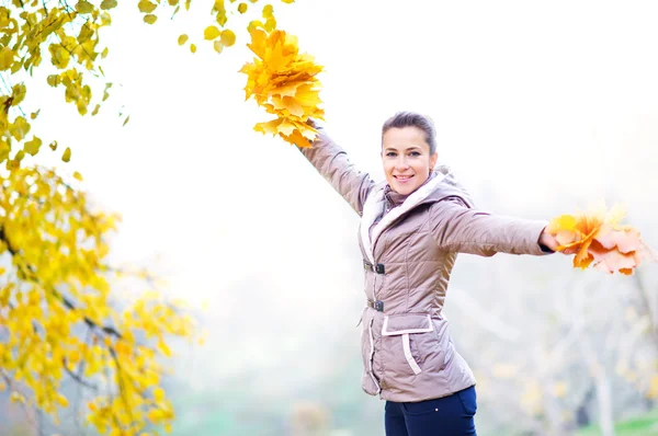 Mujer con hojas de otoño en el parque — Foto de Stock