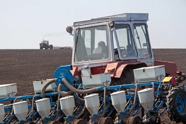 Трактор с сеялкой на поле — стоковое фото