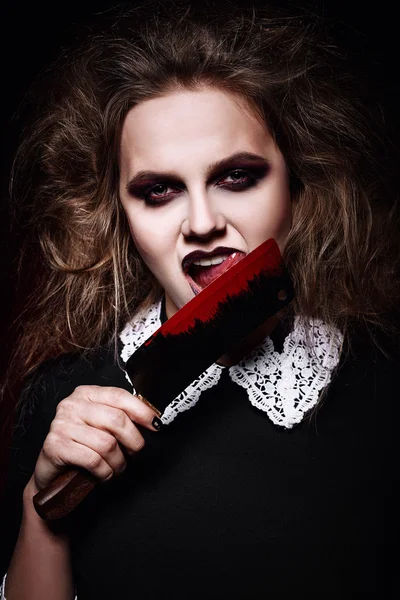 Horror shot: scary evil girl licking bloody knife