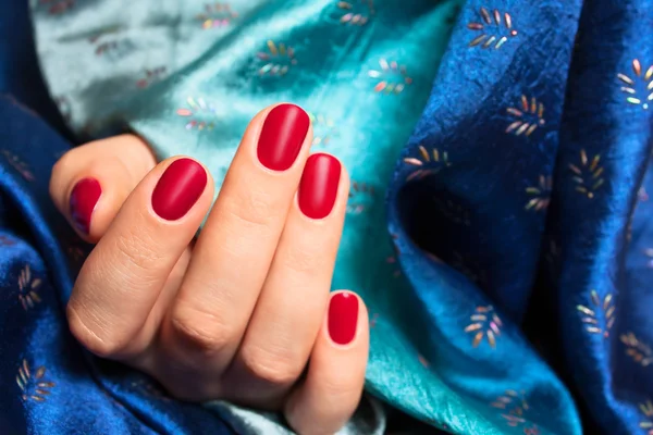 Rode nagels en blauwe zijde Stockfoto