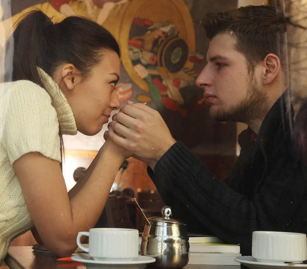 Jeune couple heureux dans un café, vue par une fenêtre — Photo