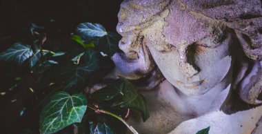 Güneş ışığındaki üzgün melek ölümün ve insan hayatının sonunun sembolü olarak. Eski bir taş heykel parçası. Yatay resim.