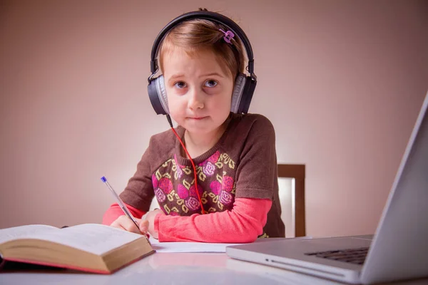 Distance education concept. Beautiful young girl learning remotely with headphones and laptop.