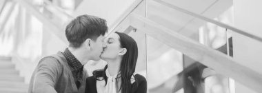 Couple in love, handsome man kisses a young beautiful woman. Black and white horizontal image.