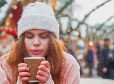Winter holidays, christmas, hot drinks and people concept. Beautiful young woman tourist in warming with hot coffee from disposable paper cup