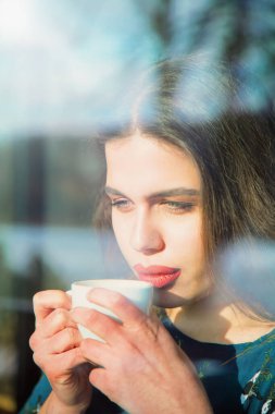 Kahve fincanıyla güzel bir kadının portresi. Bir pencerenin arkasını göster. 