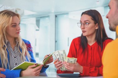 Metaphors photo of young business people holding money and analyzing financial balance of company. Stock market, office, tax, concept. 