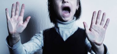 Genç kız, çocukların korku ve endişelerinin, psikolojik şiddetin ve acının sembolü olarak ağlıyor ve çığlık atıyor. Seçici odak.