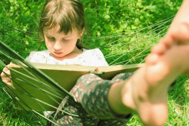 Her zaman ve her yerde öğreniyorum. Genç Beauutifuul kız hamakta kitap okuyor.