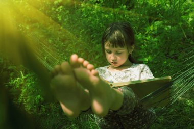 Genç, güzel bir kız, yeşil bahçedeki hamakta kitap okumaktan zevk alıyor. Gözlere seçici odaklanma