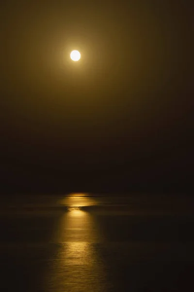 Long exposure photo. of fantastic night sea background. Moon reflecting in Mediterranean sea. Vertical image.