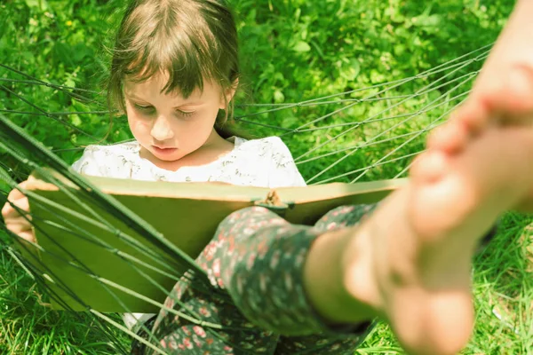 Her zaman ve her yerde öğreniyorum. Genç Beauutifuul kız hamakta kitap okuyor.
