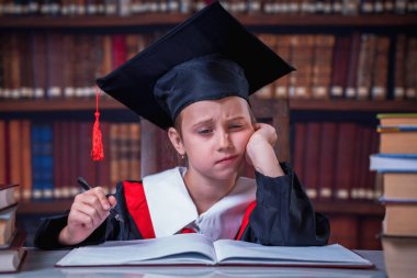 Eğitim konsepti. Manto giymiş, kütüphanede okuyan hamile kalmış güzel bir kız öğrenci..