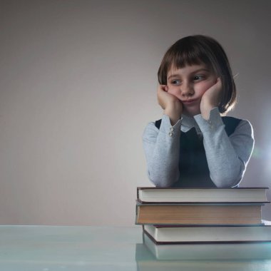 Bilgiye giden zor yolun sembolü olarak kitapları olan yorgun ve bitkin, güzel bir kız çocuğu. Portreyi kapat. Yatay resim.