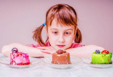 Güzel ve çekici bir genç kızın yakın portresi pastayı seçiyor. Tatil, tatlı, zevk, yemek ve çocukluk kavramı.