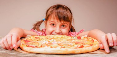 Genç ve çekici bir kız lezzetli pizzayı seviyor, bu tadı seviyor, iştahı yerinde. Kapalı alanda aç bir kadının komik görüntüsü.