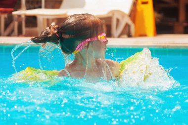 Mutlu genç kız suda eğleniyor ve havuzda yaz tatilinin tadını çıkarıyor.