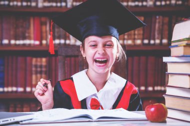 Mezuniyet şapkası içinde çok mutlu bir ustanın portresi kütüphanede gülüyor ve öğreniyor..