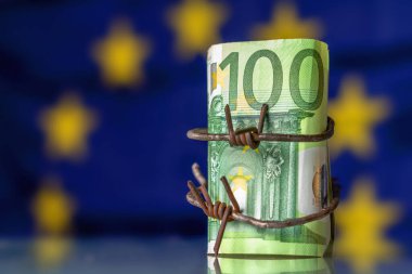 Avrupa Birliği 'nin küresel ekonomik durgunluğu ve krizi. AB bayrağına karşı dikenli tellere sarılmış 100 EURO banknotu. Tasarım için alanı kopyala.