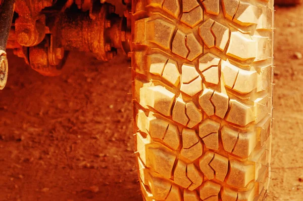 Close up wheels tires on the off-road in the dust and sand of the desert.