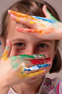 Renk, çocuklar ve kavrama konsepti. Renkli boyalı elleri olan güzel bir genç kızın portresi. Dikey resim. 