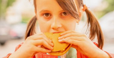 Biftekli sandviç yiyen güzel bir kızın portresi. Fast food konsepti. Yatay resim.