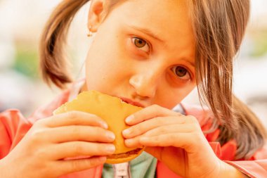 Biftekli sandviç yiyen genç ve güzel bir kız. Fast food konsepti. Yatay resim.