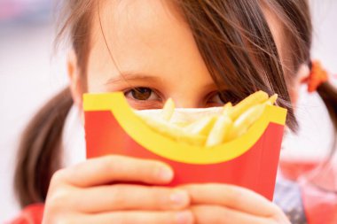 Patates kızartmalı güzel bir kızın portresini yakından çek. Sağlıksız fast food ve kalori yiyecekler. Yatay resim.