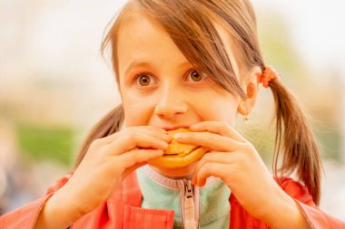 Genç ve güzel bir kız biftekli sandviç tutuyor. Fast food konsepti.