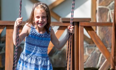 Salıncakta eğlenen güzel bir genç kızın portresi. Yaz, tatil, boş zaman ve mutlu çocukluk konsepti. Boşluğu kopyala.