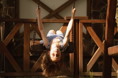 Salıncakta baş aşağı duran güzel bir genç kızın portresi. Yaz tatili ve mutlu çocukluk konsepti. 