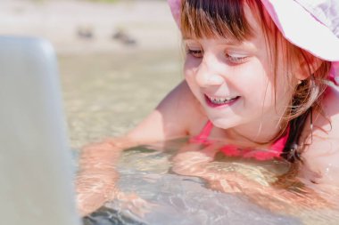 Kumsalda dizüstü bilgisayar kullanan genç ve güzel bir kız.. 