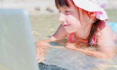 Her zaman ve her yerde öğrenme kavramı. Çok mutlu bir genç kızın portresi tropikal denizde laptopla uzaktan öğreniyor..